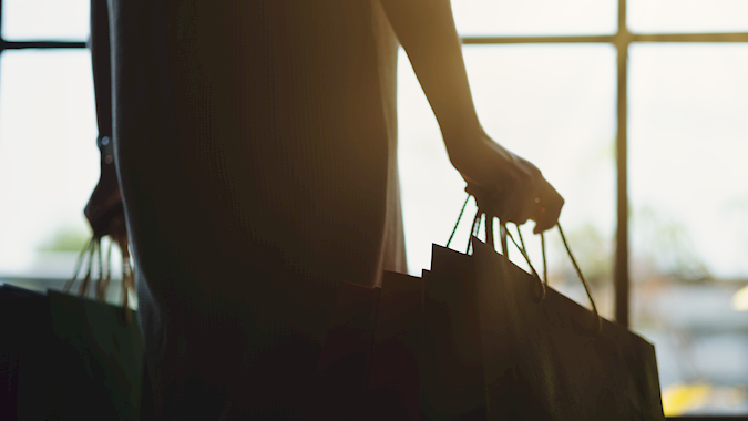 Silhouette of a shopper carrying bags in natural light, symbolizing the final step in a seamless and efficient retail logistics journey.